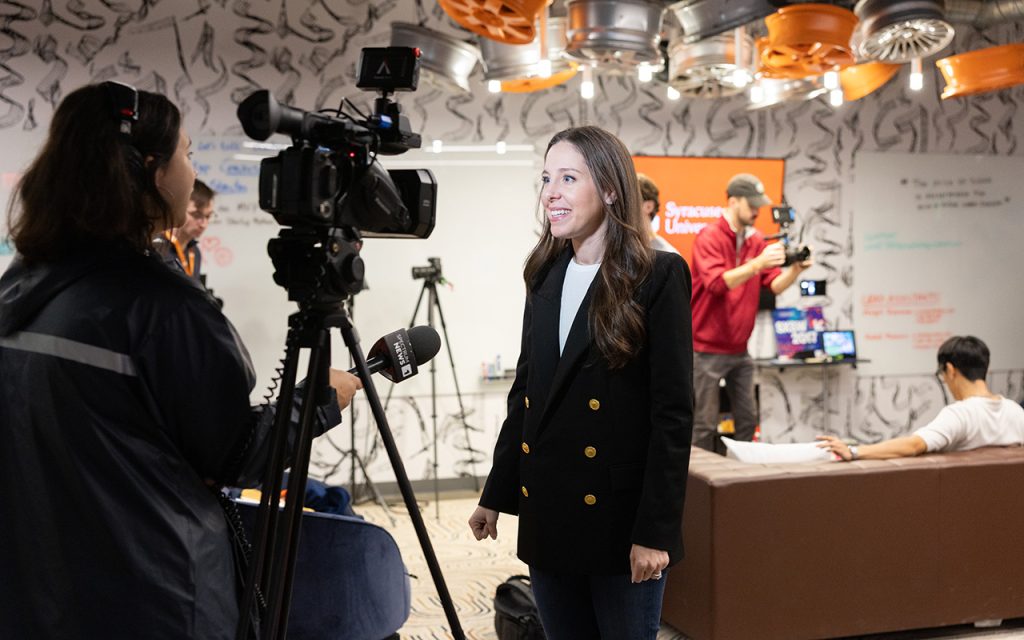 A woman prepares to speak in front of a TV camera at the CUSE Creator Con