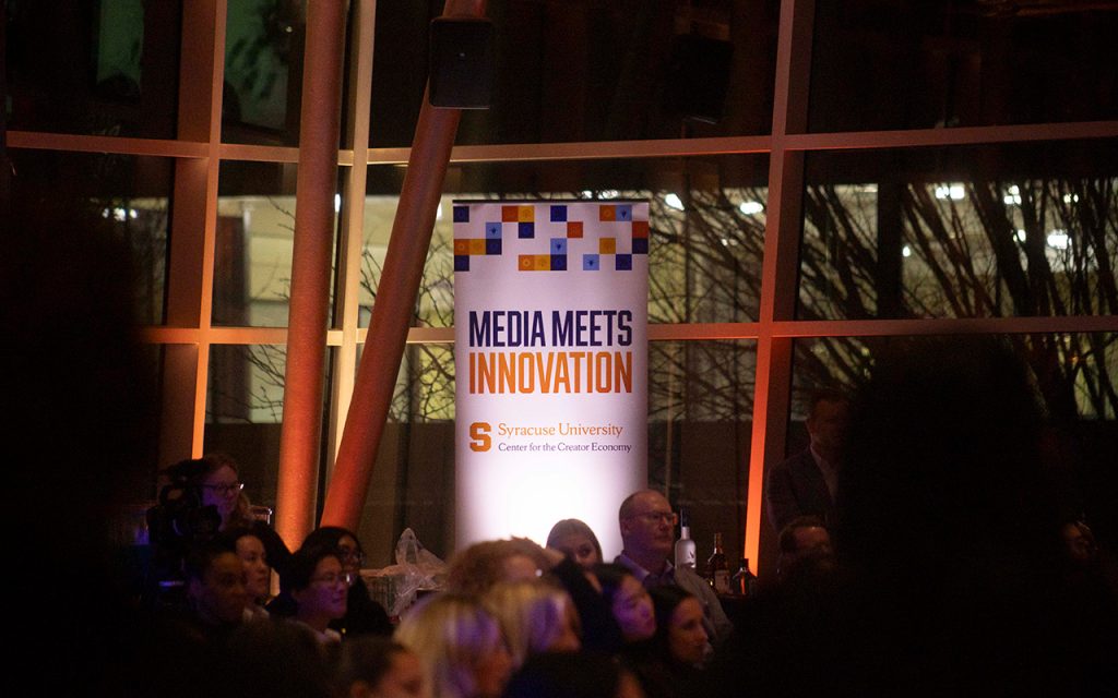 Media Meets Innovation banner is seen in the background as an audience listens to remarks