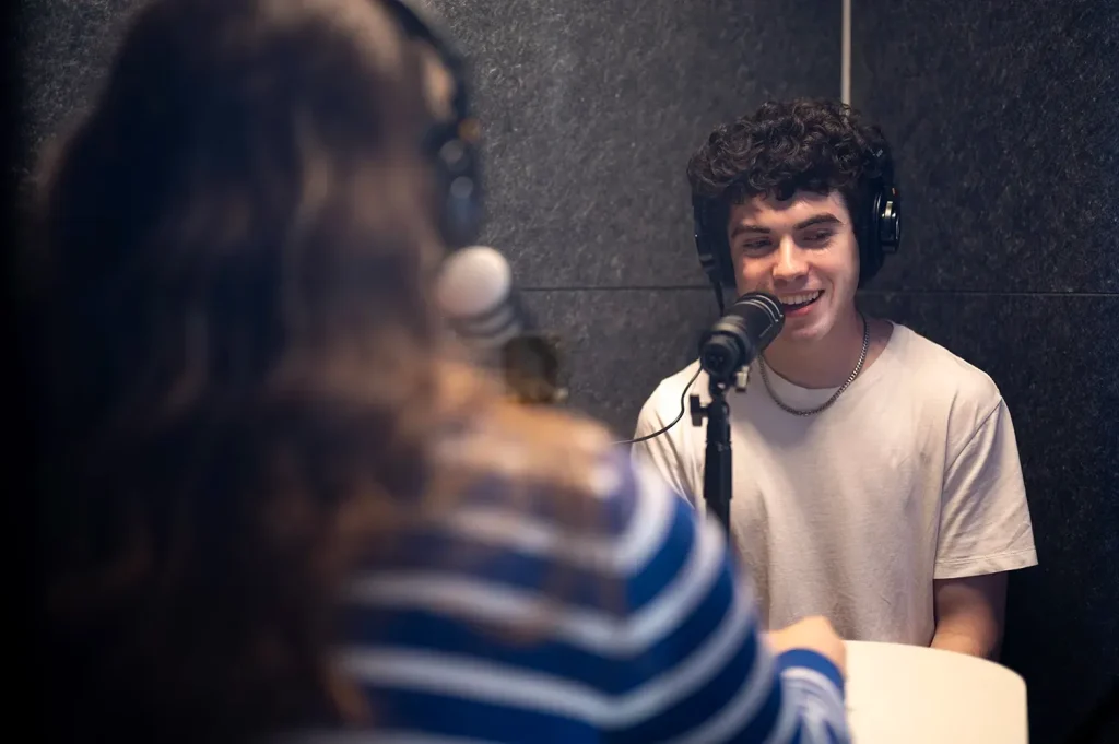 Two people recording in a podcast booth