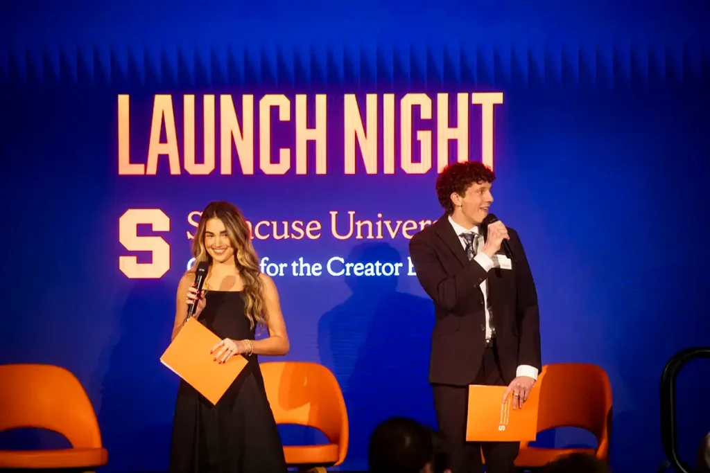 Two student hosts holding microphones on stage at the Center for the Creator Economy's Launch Night event